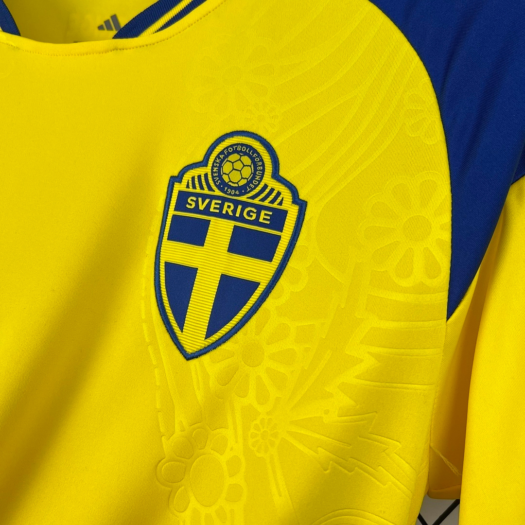 Dettaglio_stemma_Svezia_e_texture_floreale_su_maglia_home_2026.png