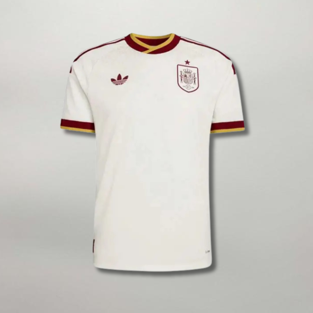 Fronte_della_maglia_away_della_Spagna_2026_bianca_con_dettagli_bicolore_sul_colletto_e_stemma_centrale_ricamato.png