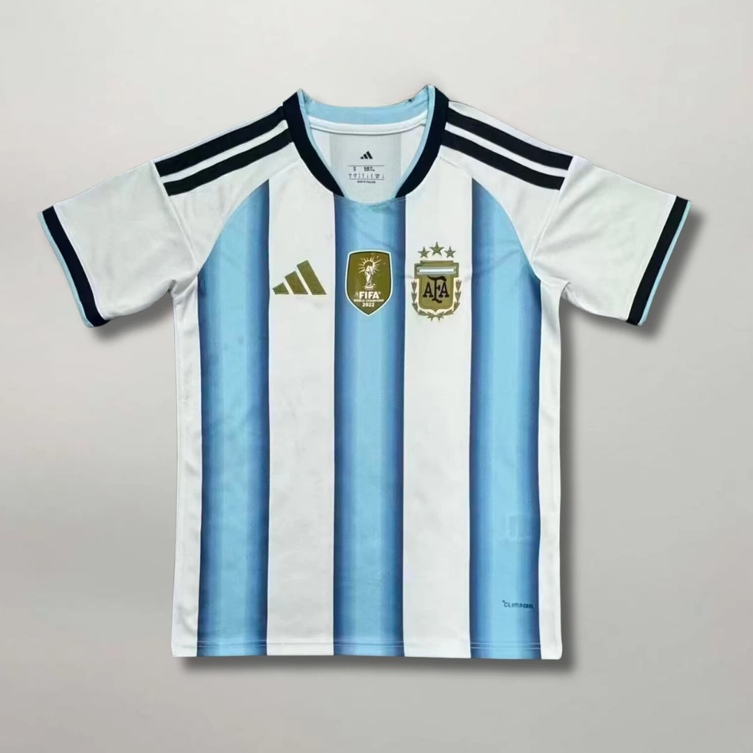 Fronte_della_maglia_home_Argentina_2026_a_strisce_bianche_e_celesti_con_dettagli_dorati_e_stemma_ricamato_sul_petto