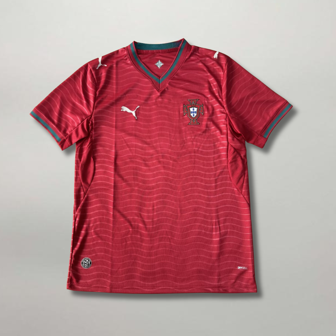 Fronte_della_maglia_home_Portogallo_2026_rosso_scuro_con_trama_a_micro-righe_orizzontali_e_stemma_ricamato_sul_petto.png