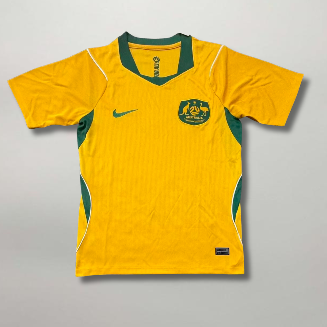 Fronte_della_maglia_home_dell_Australia_2026_oro_con_inserti_verdi_e_stemma_ufficiale_ricamato_sul_petto.png